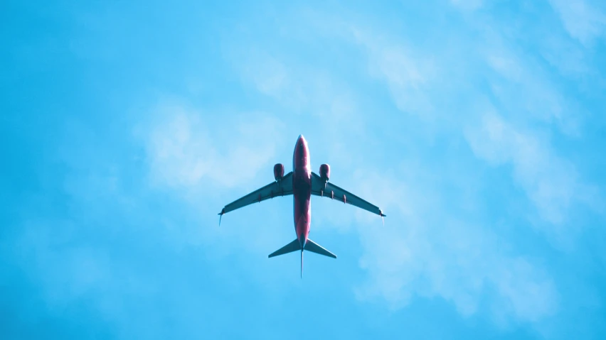 the underside view of an airplane flying in the blue sky