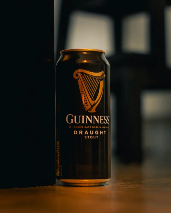 a beer can sitting on a table with a black wall in the background