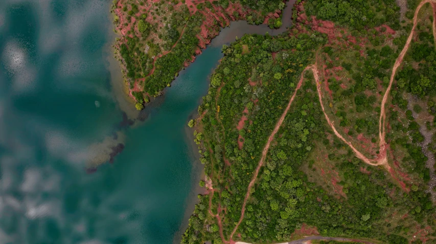 an aerial view of the river, surrounded by some trees and green grass