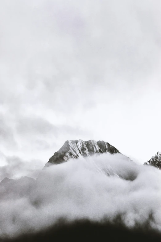 a mountain covered in mist and snow with snow capped peaks