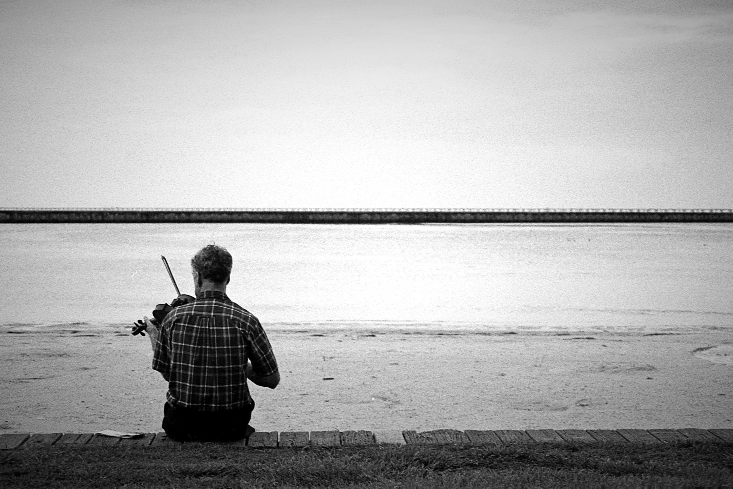 a man holding a violin on top of the beach