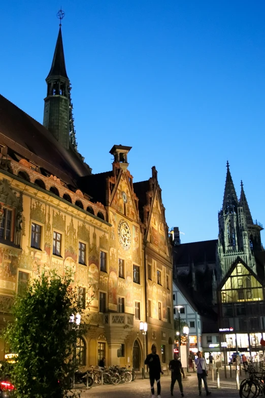 people in an old european town square at night