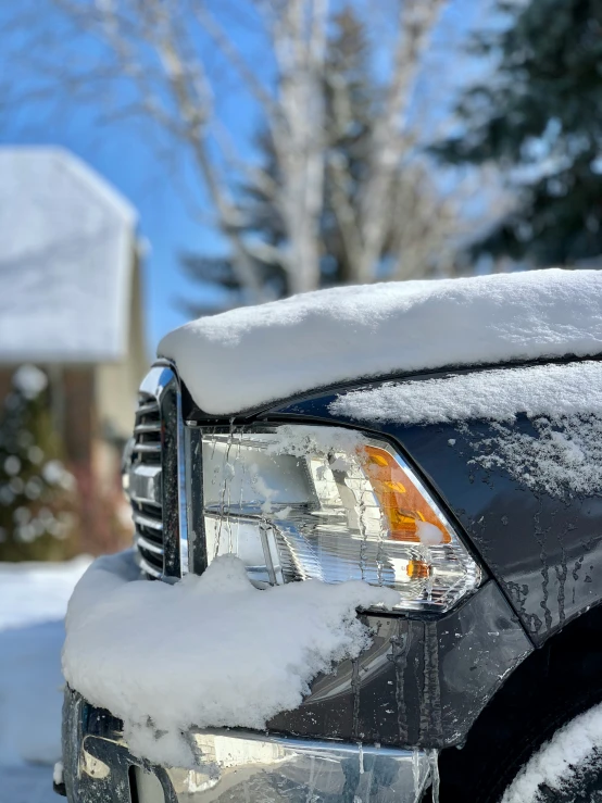 the headlights on a black truck covered in snow