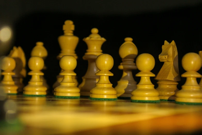 yellow and green chess pieces stand out against the black background