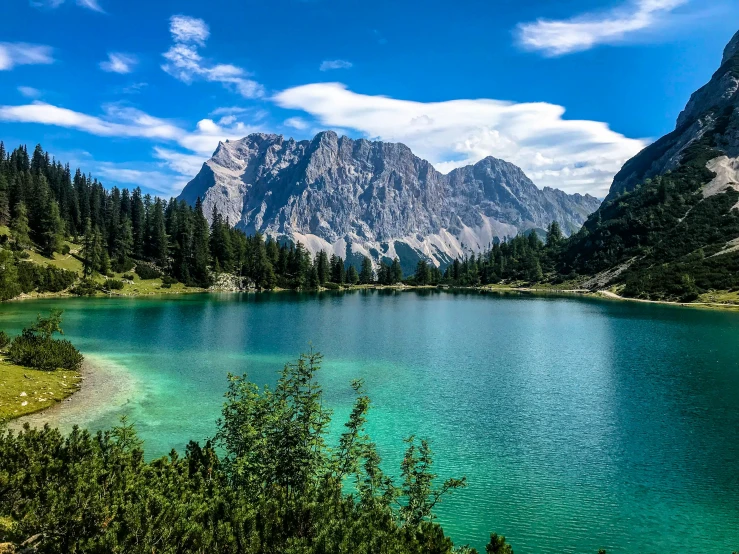 the blue lake is surrounded by mountains and pine trees