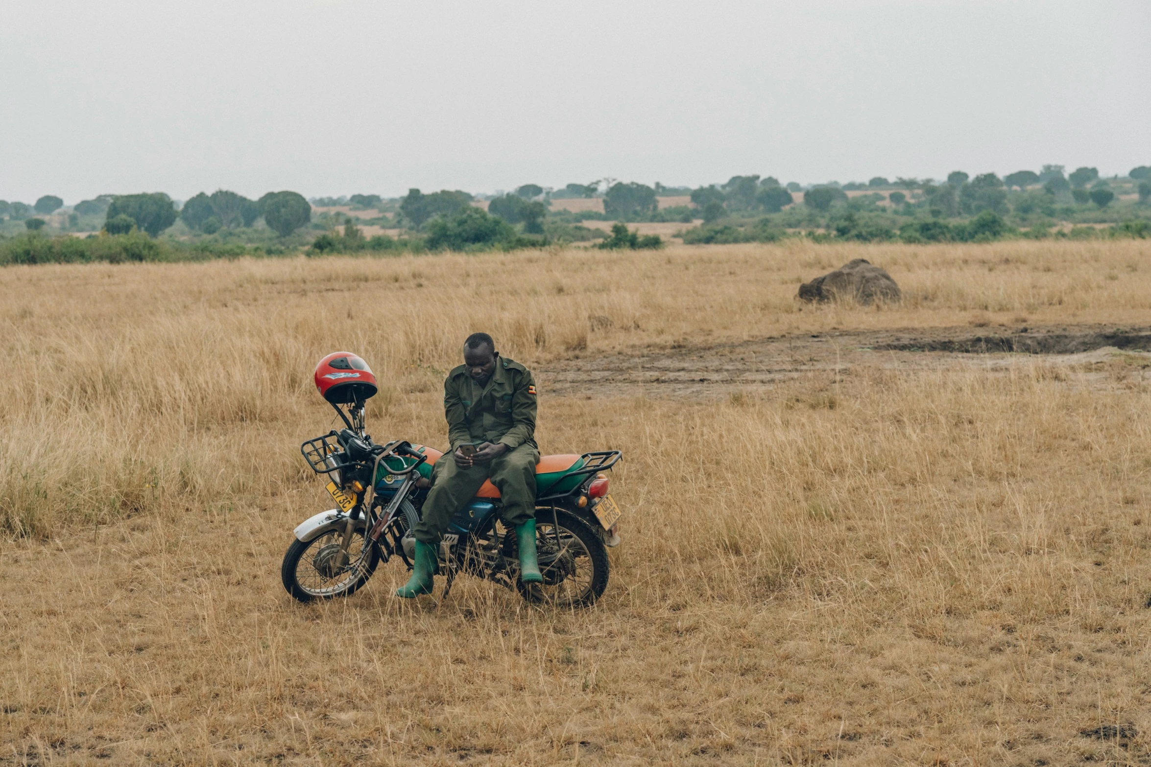 two people standing behind a motorcycle in a field