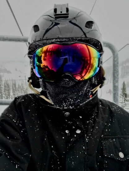 a man wearing goggles, standing in front of a ski lift