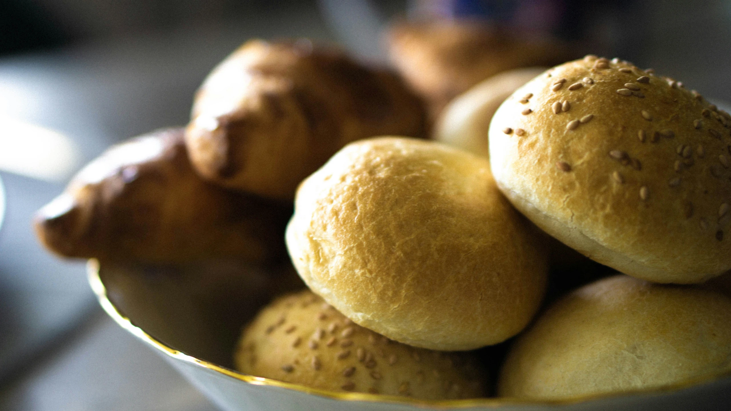 a white bowl filled with rolls on top of a table