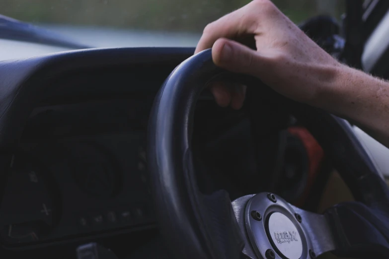 man driving in a vehicle holding the steering wheel
