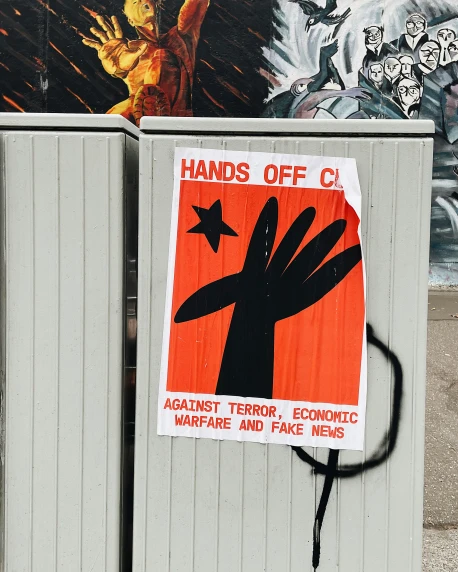 a street sign, in front of a wall with graffiti, that reads hands off