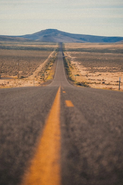 a lone yellow line in the middle of a desert road