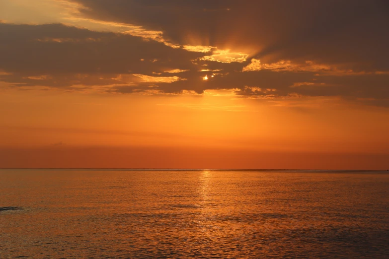 a boat in the ocean at sunset with a sky background