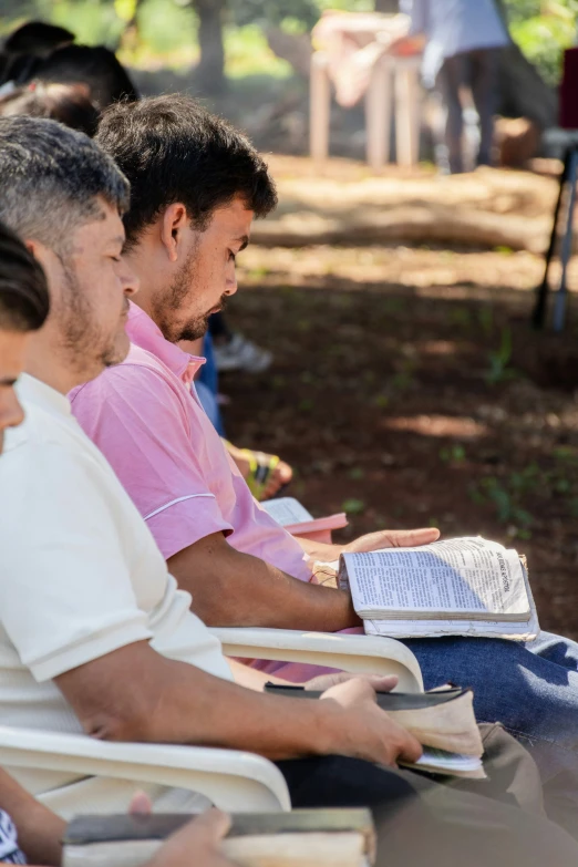 several men sitting and one reading a book