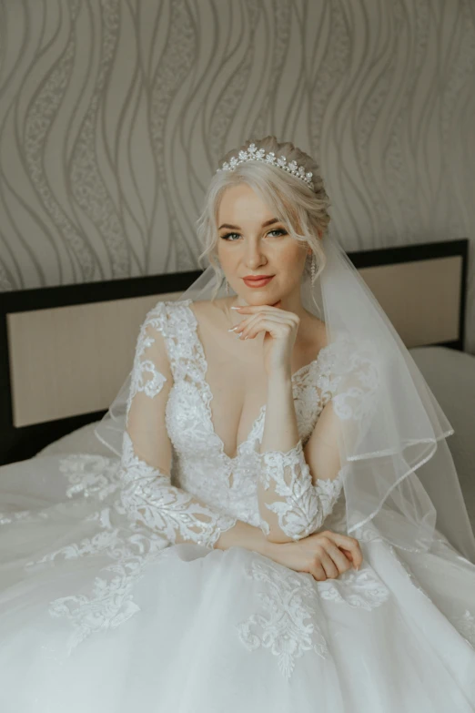 a woman sitting on top of a bed in a wedding dress