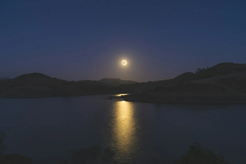 a full moon in the distance on a night sky