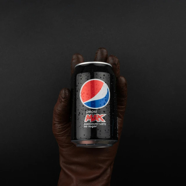 a person's hand holding a can of pepsi