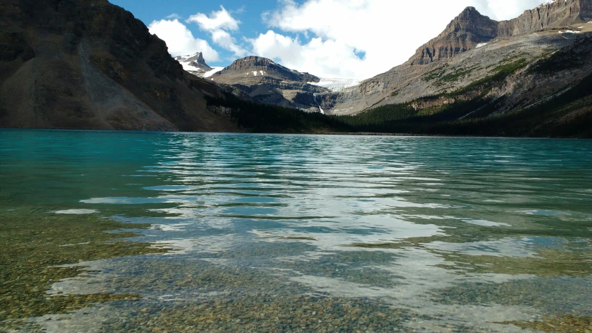 the water is very clear and there are few clouds above it