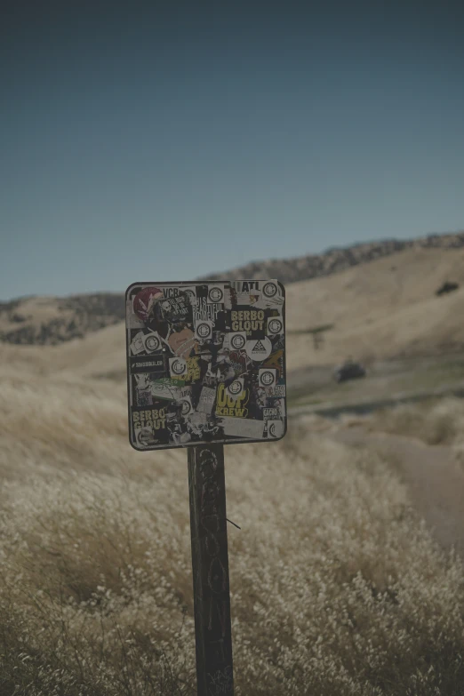 a sign with stickers on it is in the middle of a field