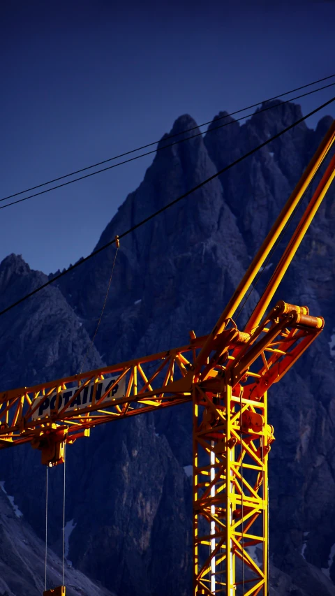 a large crane standing in front of a mountain