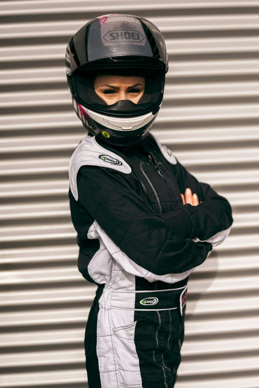 a person posing in front of a garage door wearing a racing suit