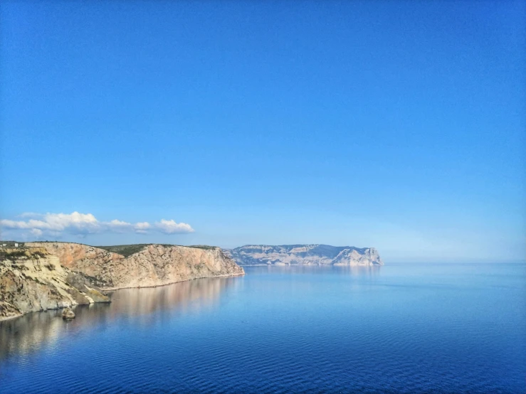 the ocean that is blue and clear with a small boat in it