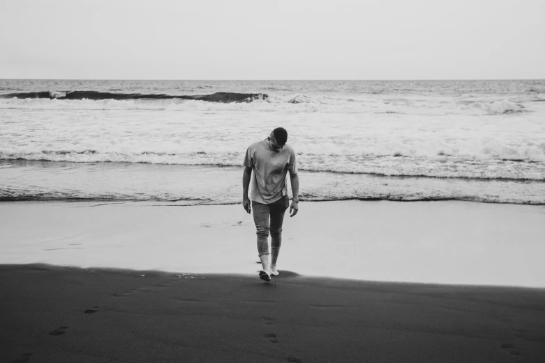 a man walking on the beach holding a frisbee