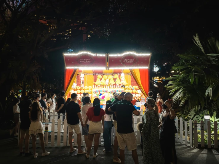 people stand at the top of a white fence and watch a circus