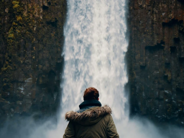 a man standing in front of a waterfall