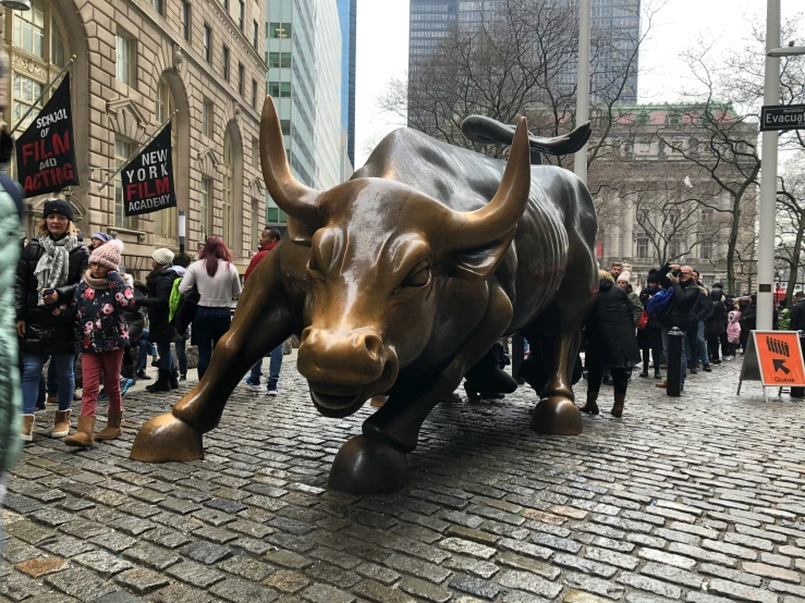 a group of people standing near a large statue of a bulls