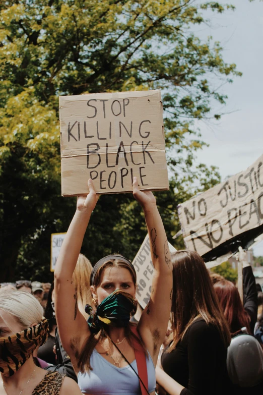 a woman holding a sign while protesting against ing black people