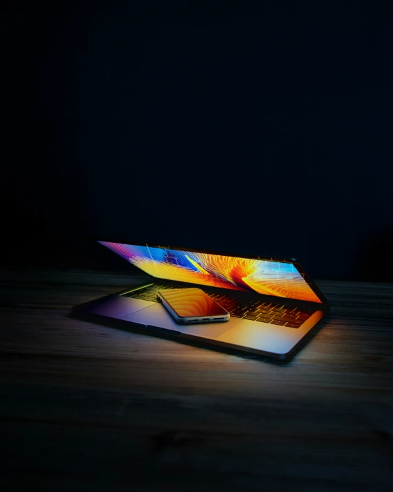 the illuminated laptop sits on a wooden table