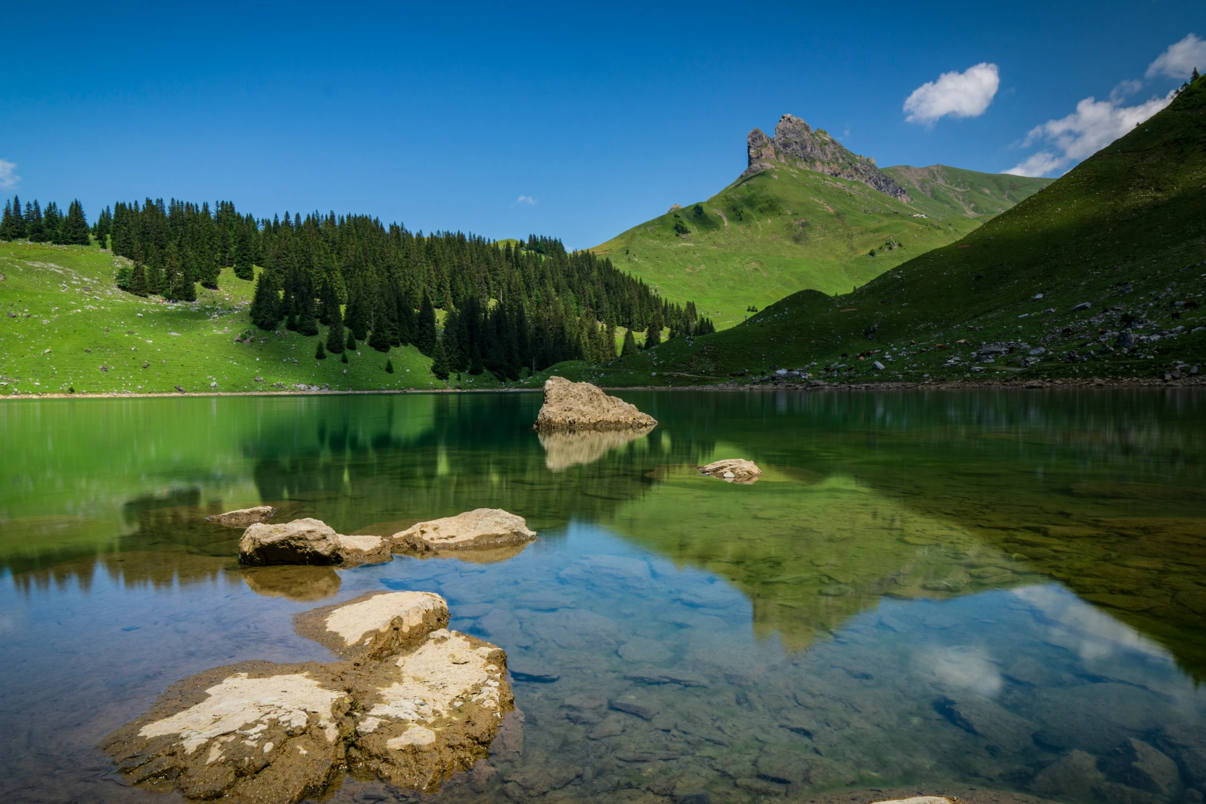 the water is crystal and calm at the base of a mountain