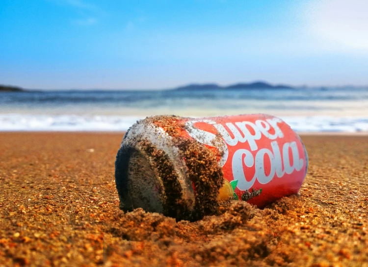 an old coke cola can that is lying in the sand