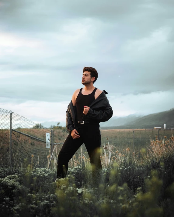 a man is wearing a large jacket and standing near bushes