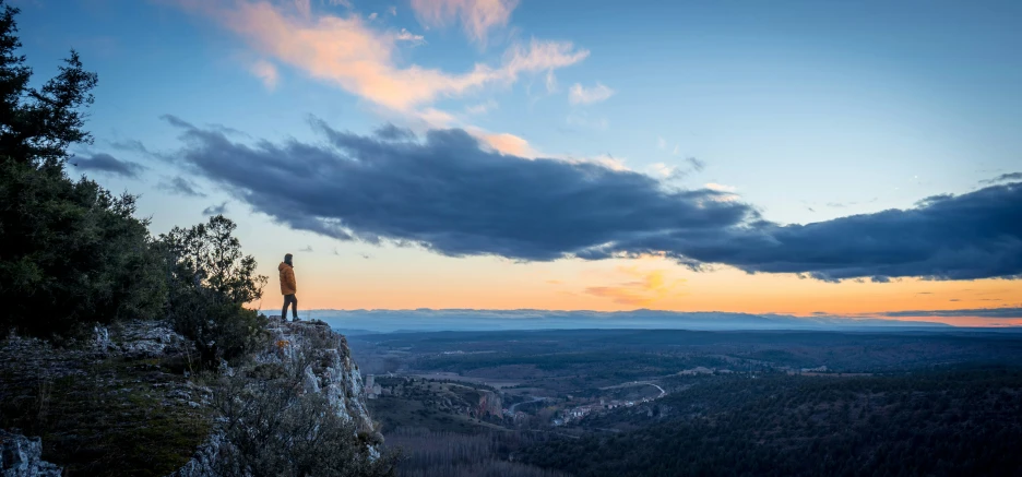 two people stand on a rock above a valley