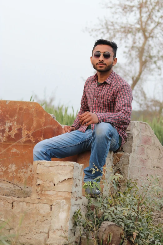 a man sitting on a stone wall with sunglasses on