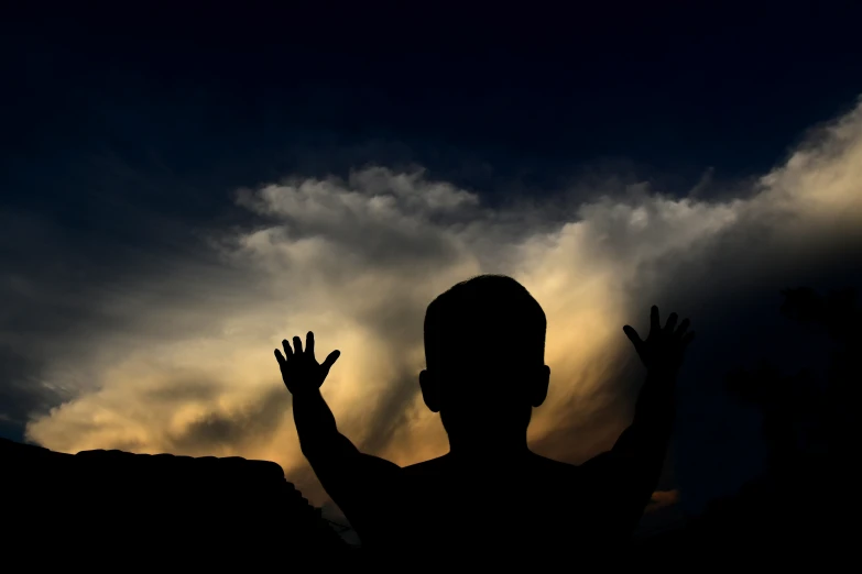 a man raising his hands in the air to catch the sun
