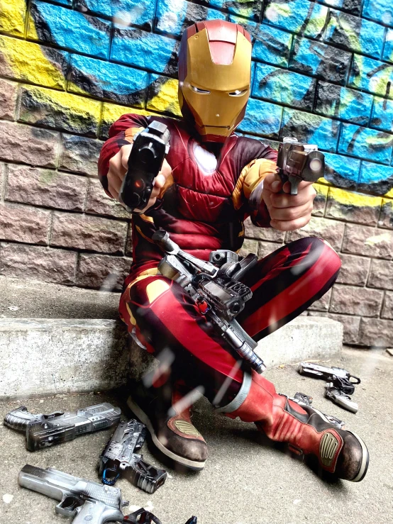 a man sitting on the ground with lots of guns