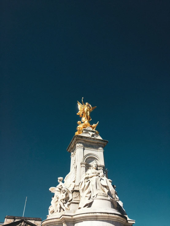 a very tall white and gold statue on top of a tall building