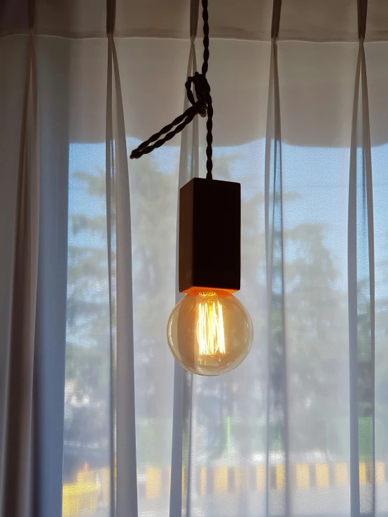 the light bulb is hanging from the curtains