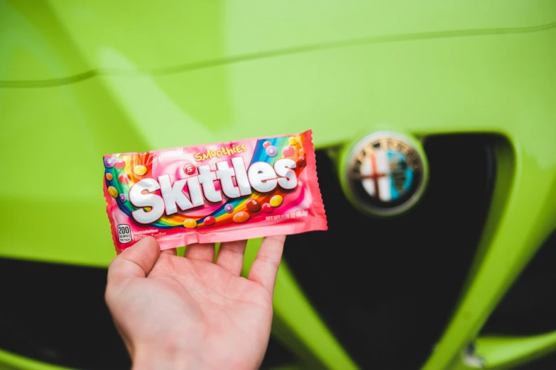 a hand holding a candy bar with skittles on it