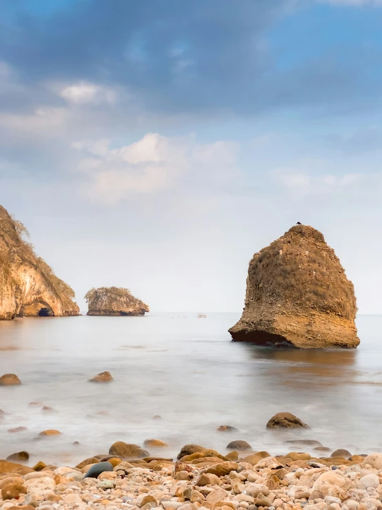 several large rocks on the shore line, with an ocean in the background