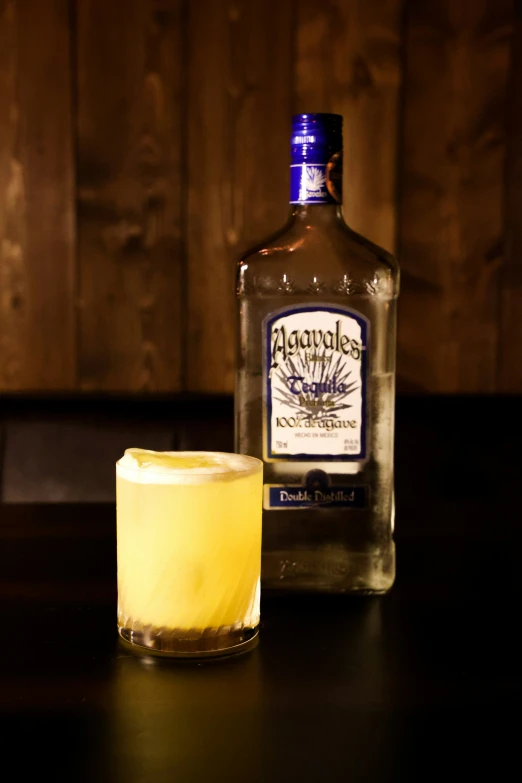 an alcoholic beverage sits on a table next to a drink