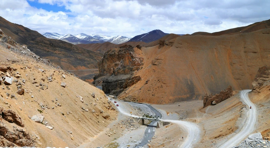 two roads going through the mountainous area with snow capped mountains