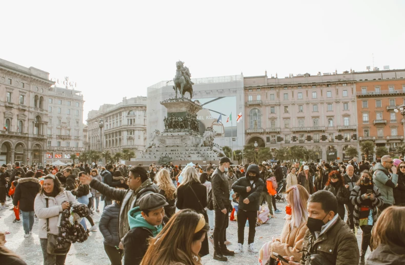 a crowd of people standing next to a statue in the middle of the road