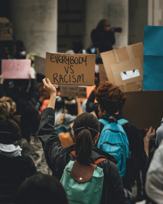 a person holding a sign with the words childishdom vs racism