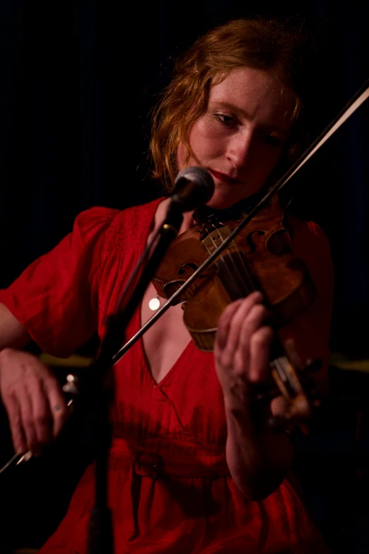 woman holding up violin and looking into microphone