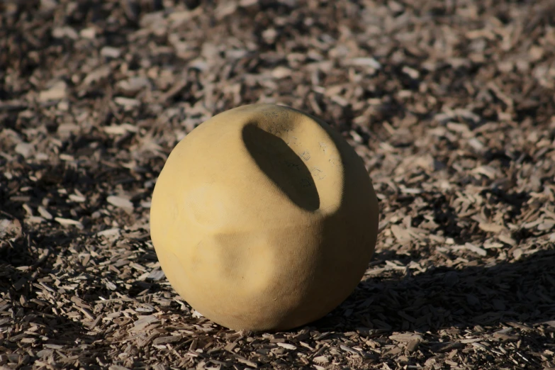 a circular, yellow vase is sitting on the ground