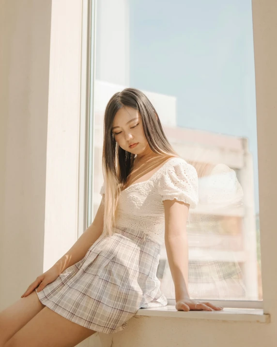 an asian woman posing for a picture while leaning on the window sill