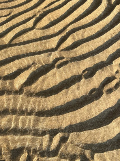 footprints on the beach sand with wavy patterns